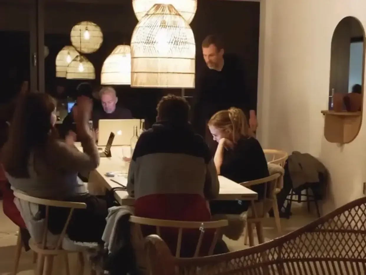 Eine Gruppe von Menschen sitzt mit Laptops um einen Tisch