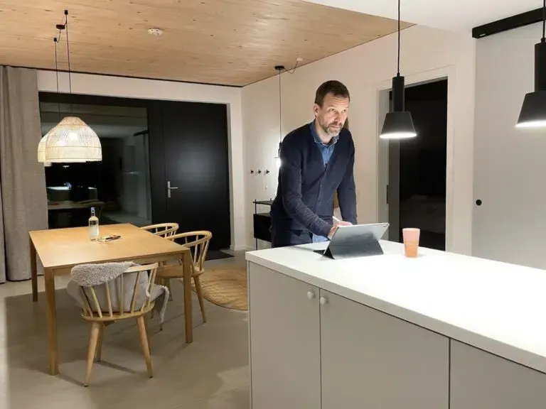 Ein Mann steht in einer Küche und benutzt einen Tablet-Computer.