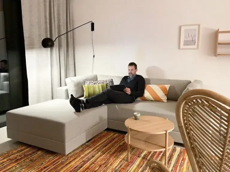 Ein Mann liegt auf einer Couch und benutzt einen Laptop.