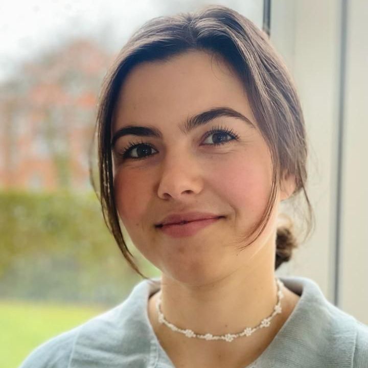 A woman wearing a necklace is smiling for the camera