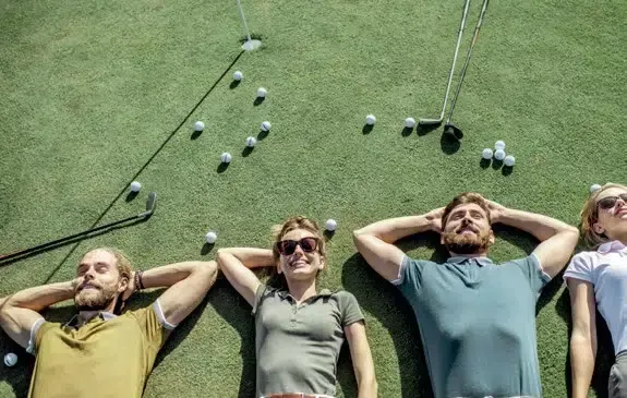 Eine Gruppe von Leuten liegt mit Golfbällen auf einem Golfplatz.