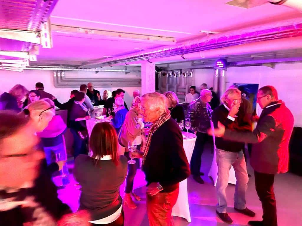 Eine Gruppe von Menschen tanzt in einem Raum mit violettem Licht.