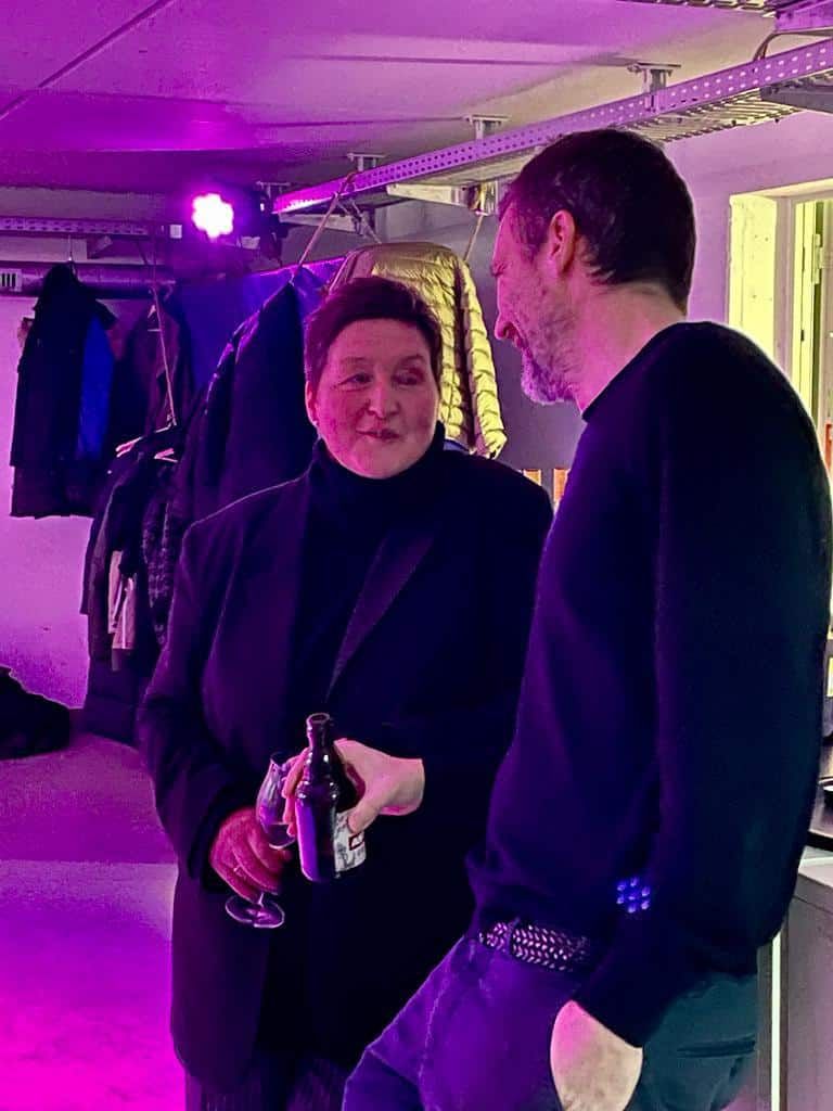 Ein Mann und eine Frau stehen nebeneinander in einem Raum mit violettem Licht.