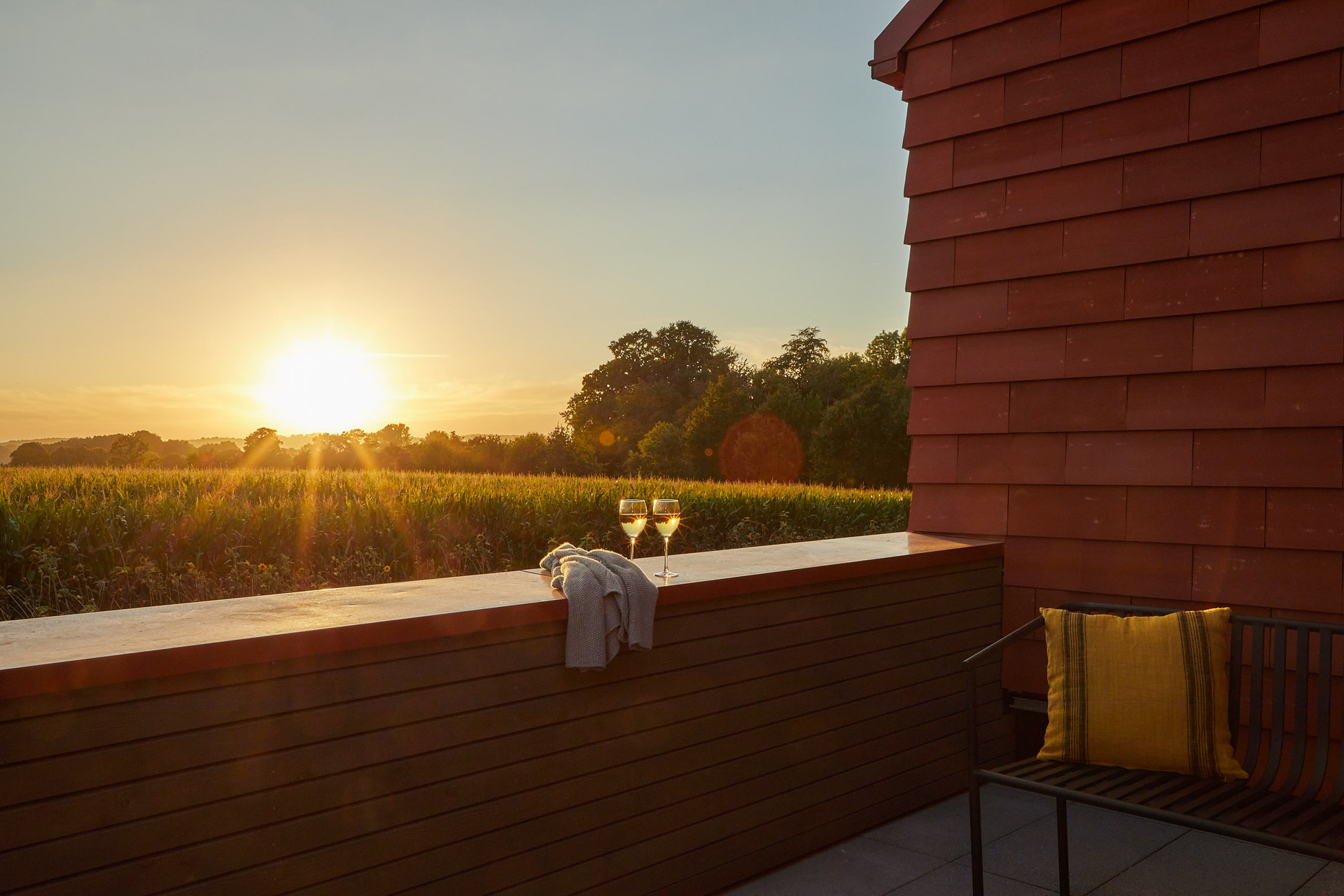 Ein Balkon mit Blick auf ein Feld und einen Sonnenuntergang.