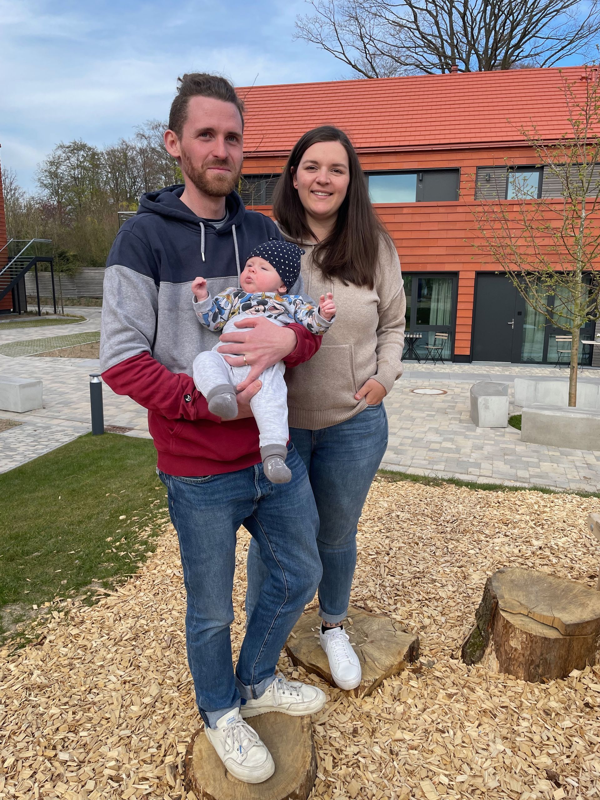 A man and woman are standing next to each other holding a baby.