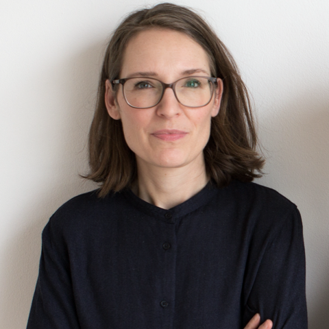 A woman wearing glasses and a black shirt with her arms crossed