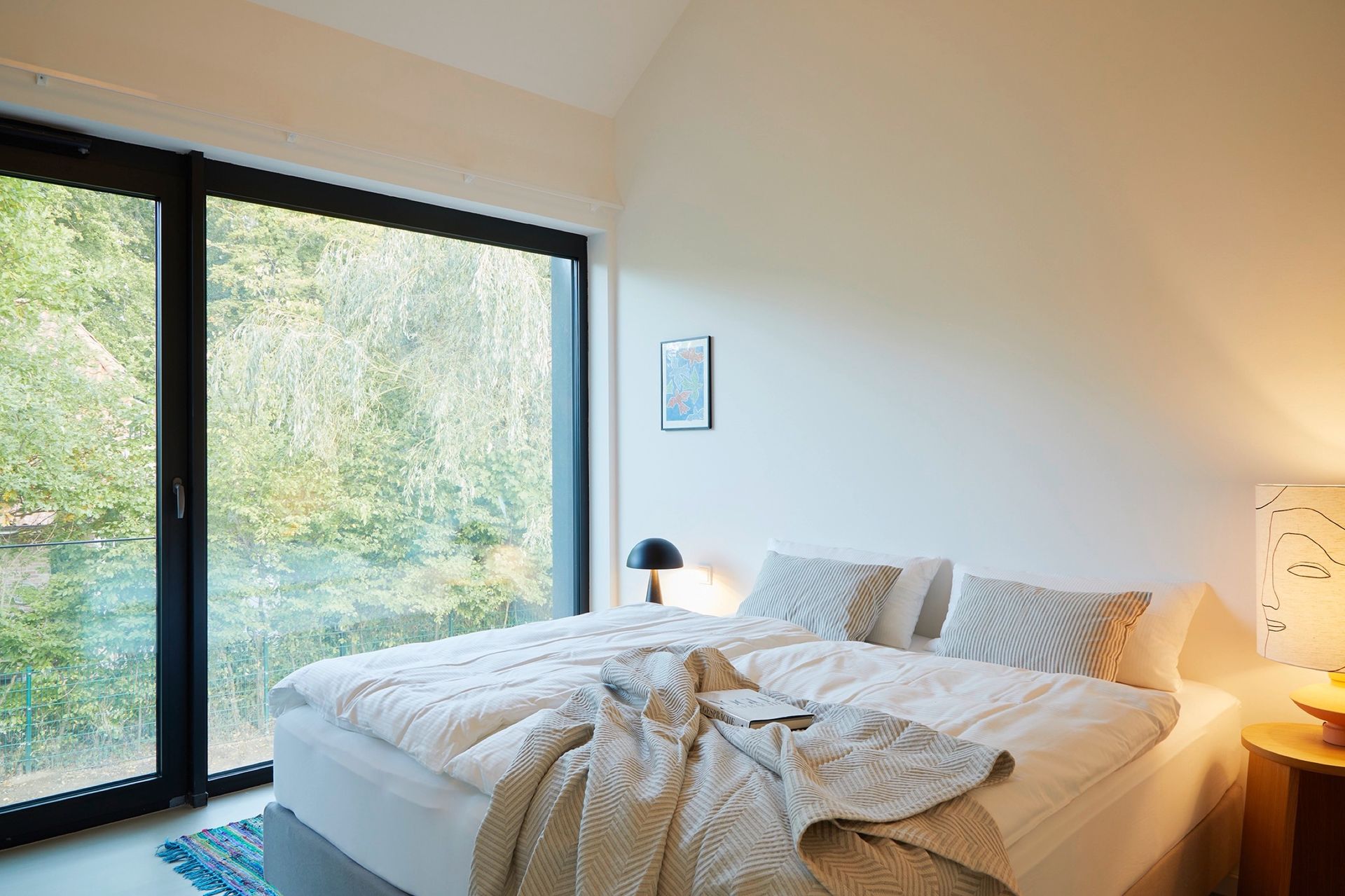 Ein Schlafzimmer mit großem Bett und großem Fenster.