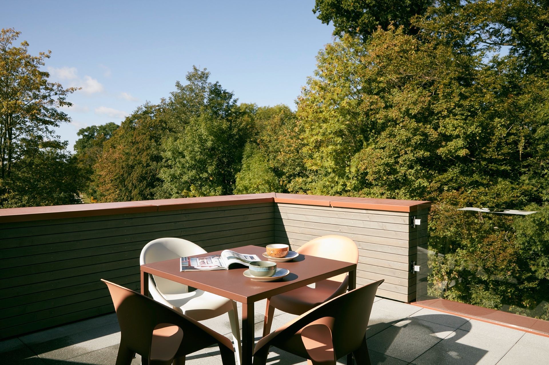 A table and chairs on a balcony with trees in the background