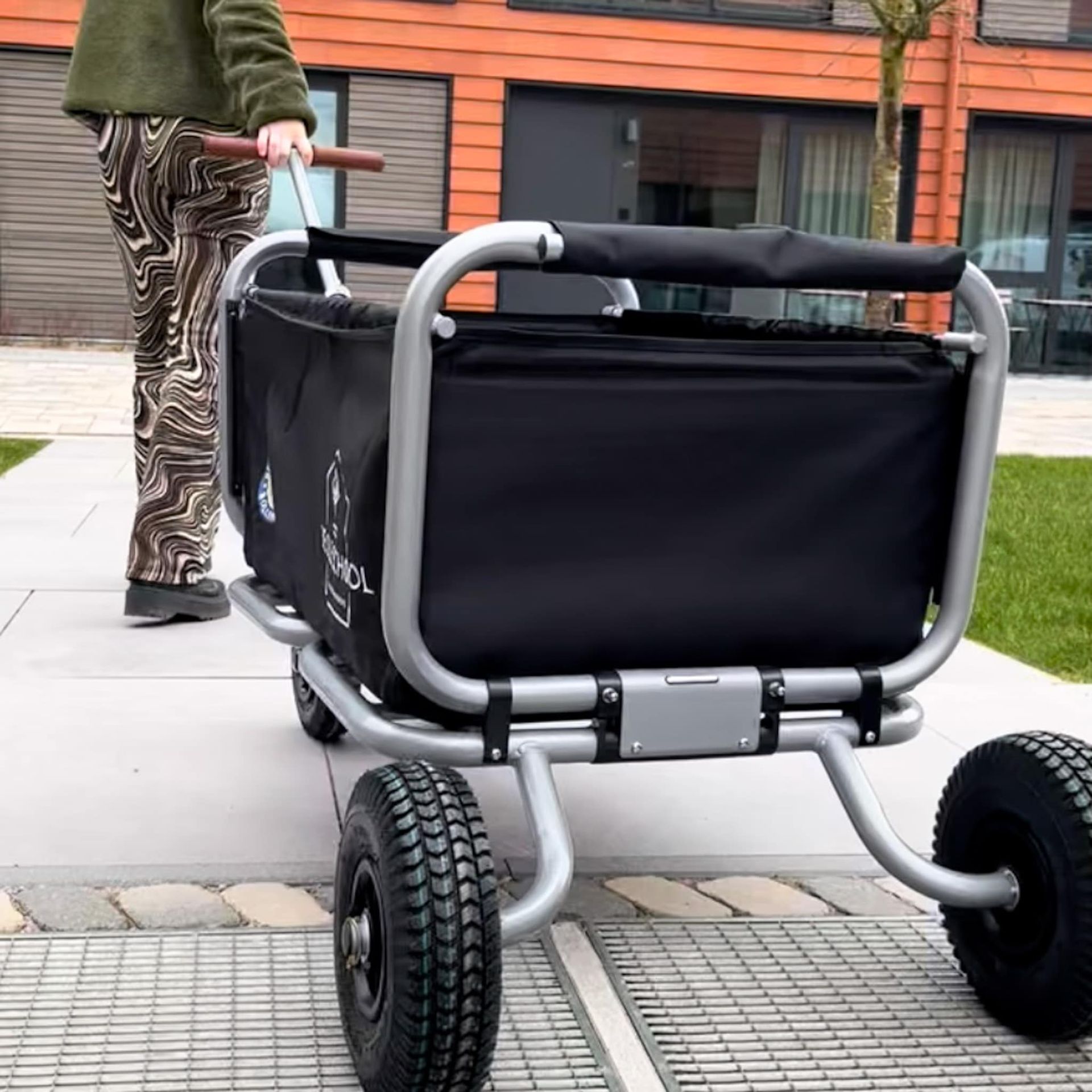 Eine Person schiebt einen schwarzen Wagen auf Rädern