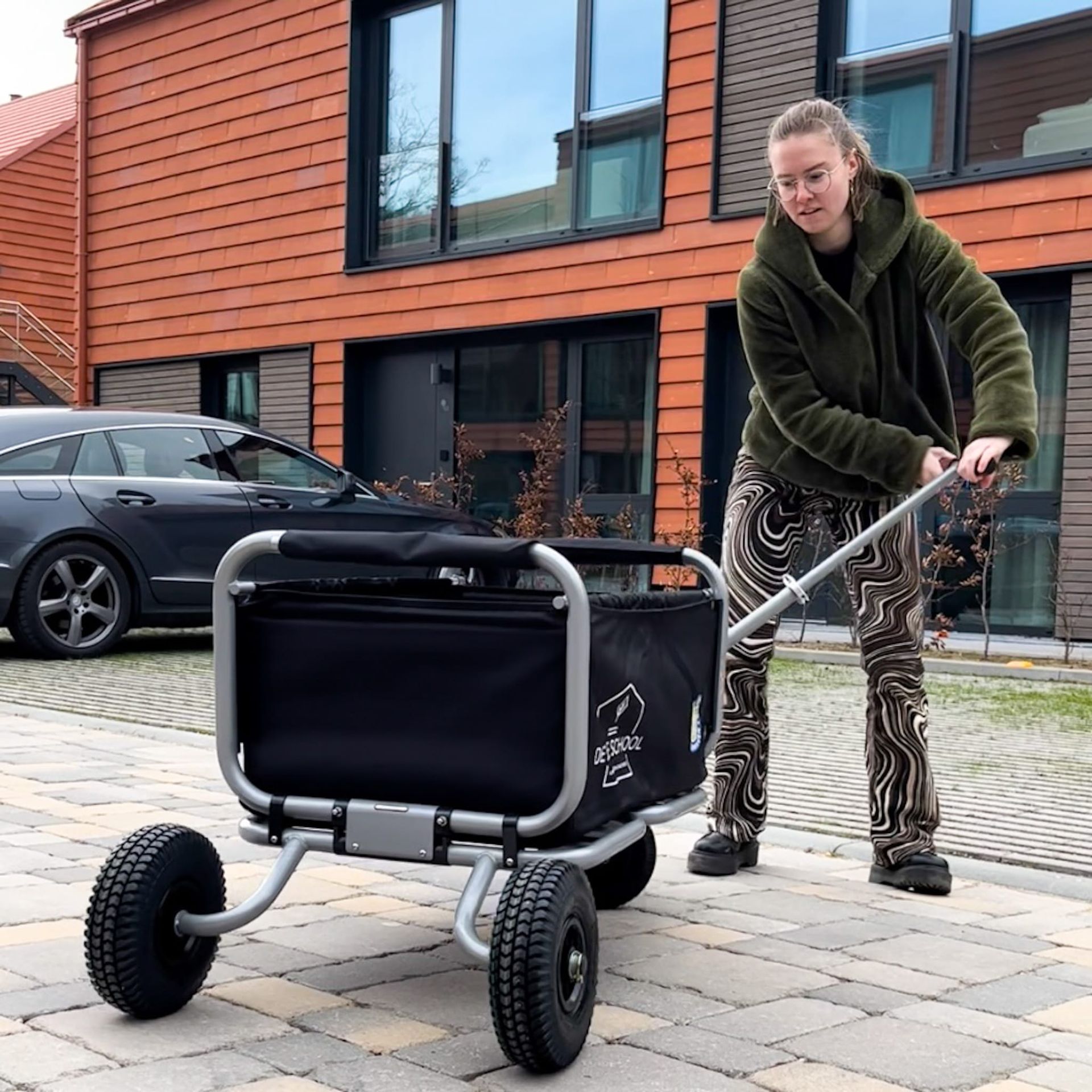 Eine Frau schiebt einen Wagen mit einer schwarzen Tasche darauf