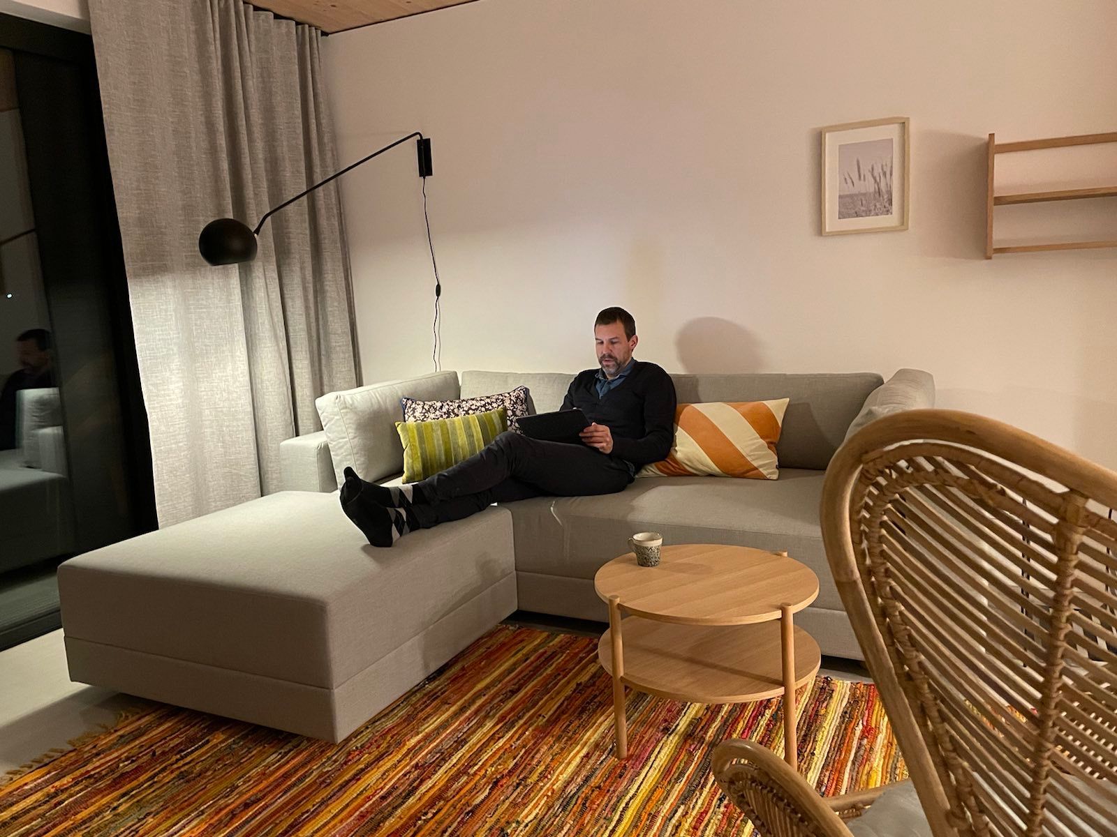 Ein Mann sitzt auf einer Couch in einem Wohnzimmer und benutzt einen Laptop.