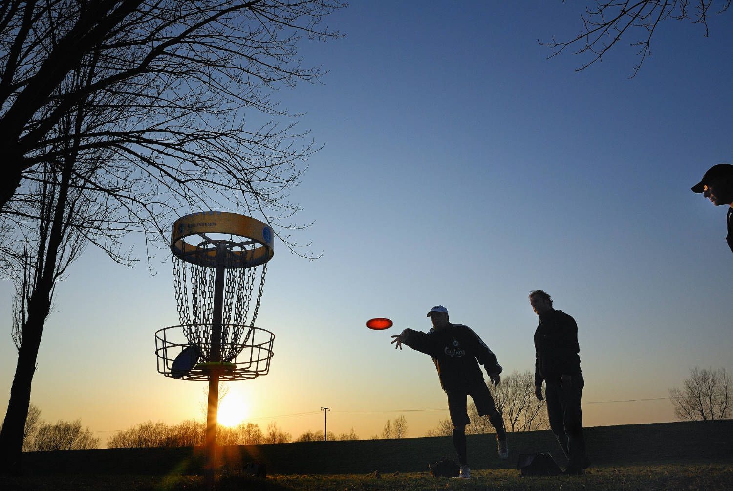 Eine Gruppe von Leuten spielt Disc-Golf bei Sonnenuntergang