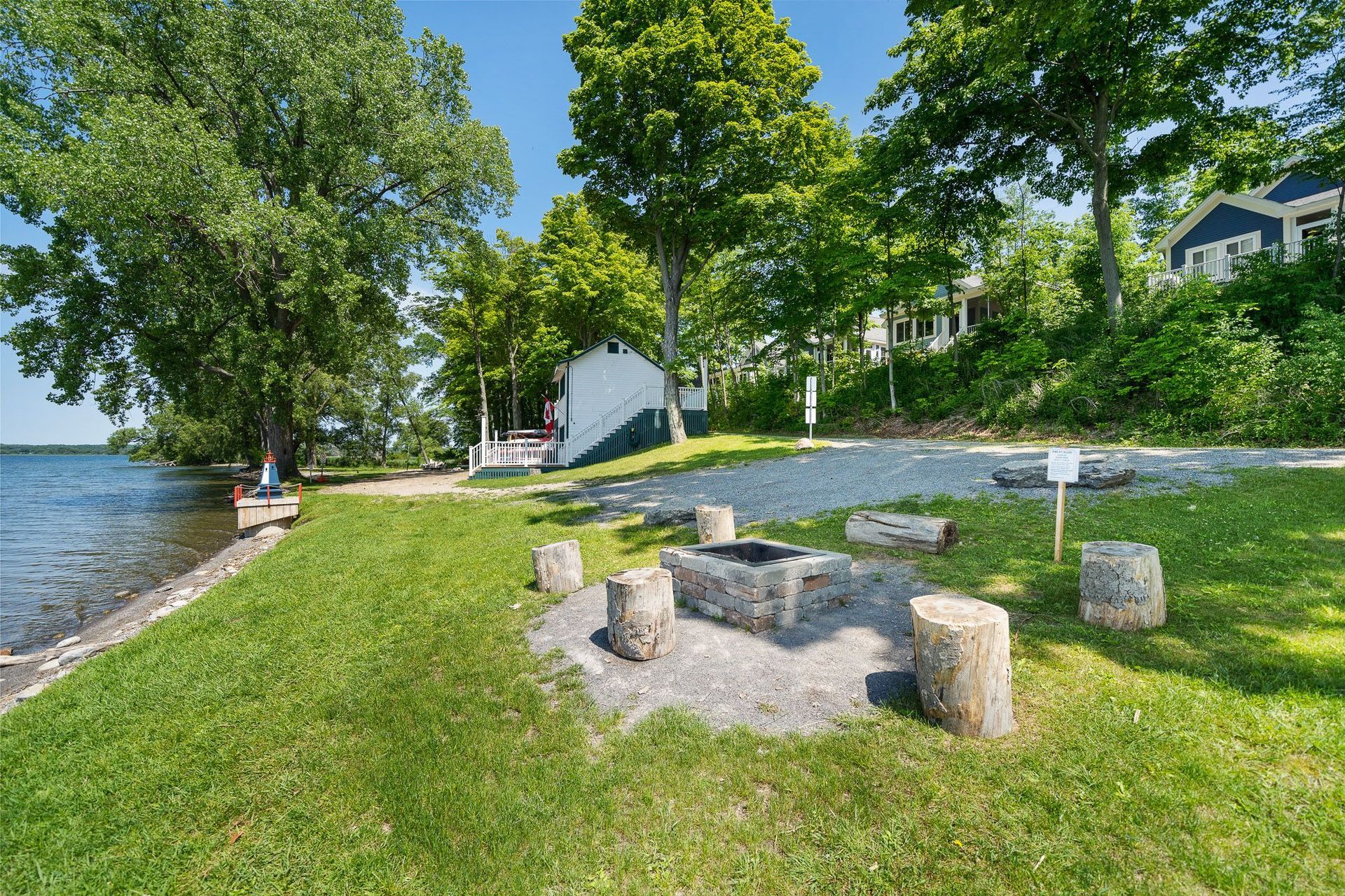 There is a fire pit in the middle of the grass near the water.