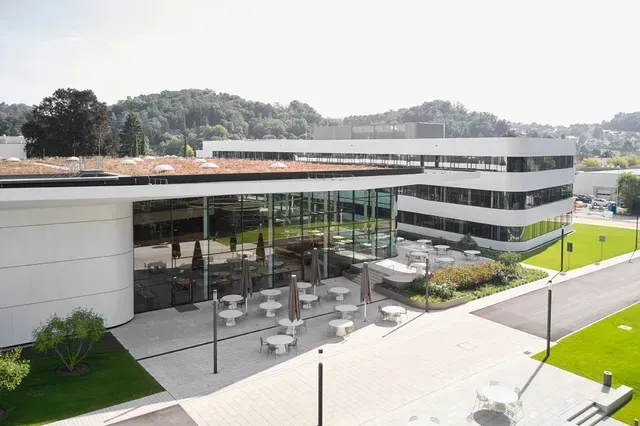 Eine Luftaufnahme eines großen weißen Gebäudes mit Tischen und Stühlen von Paul Hartmann AG, Neubau Forum und Office.