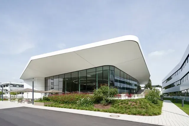 Ein großes weißes Gebäude mit einem geschwungenen Dach und vielen Fenstern