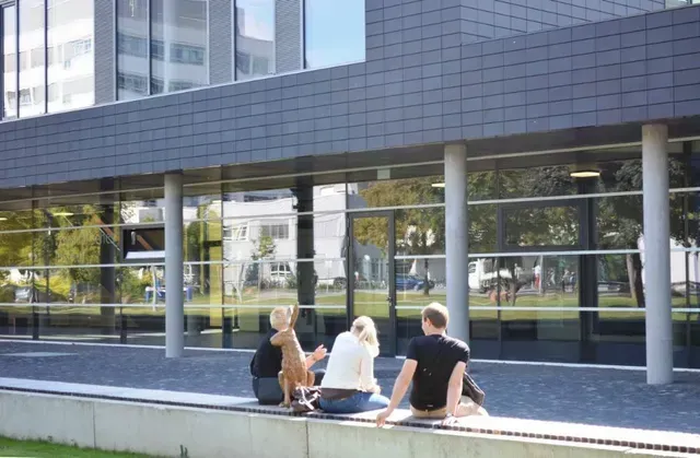 Eine Gruppe von Menschen sitzt mit einem Hund vor einem Gebäude