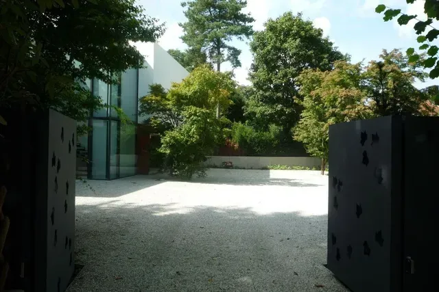 Eine Auffahrt, die zu einem Haus mit Bäumen im Hintergrund führt vom Hausgarten in Erlangen