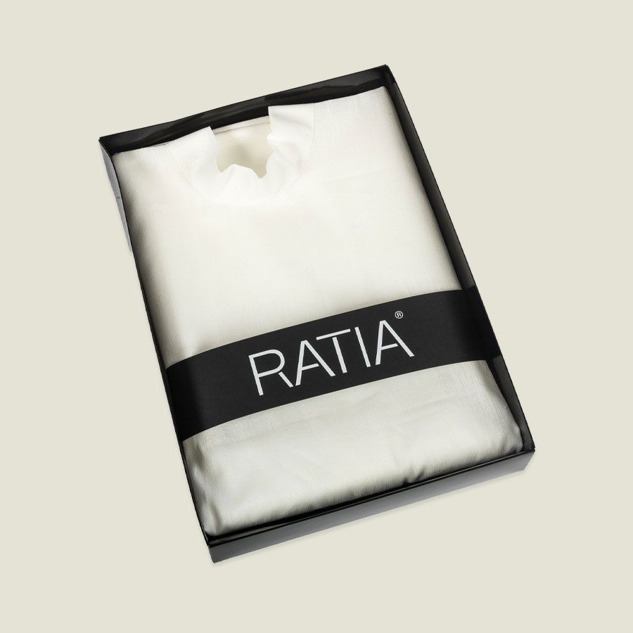 Valkoinen taiteltu vaate mustareunaisessa pakkauksessa, jossa on merkintä ”RATIA”
