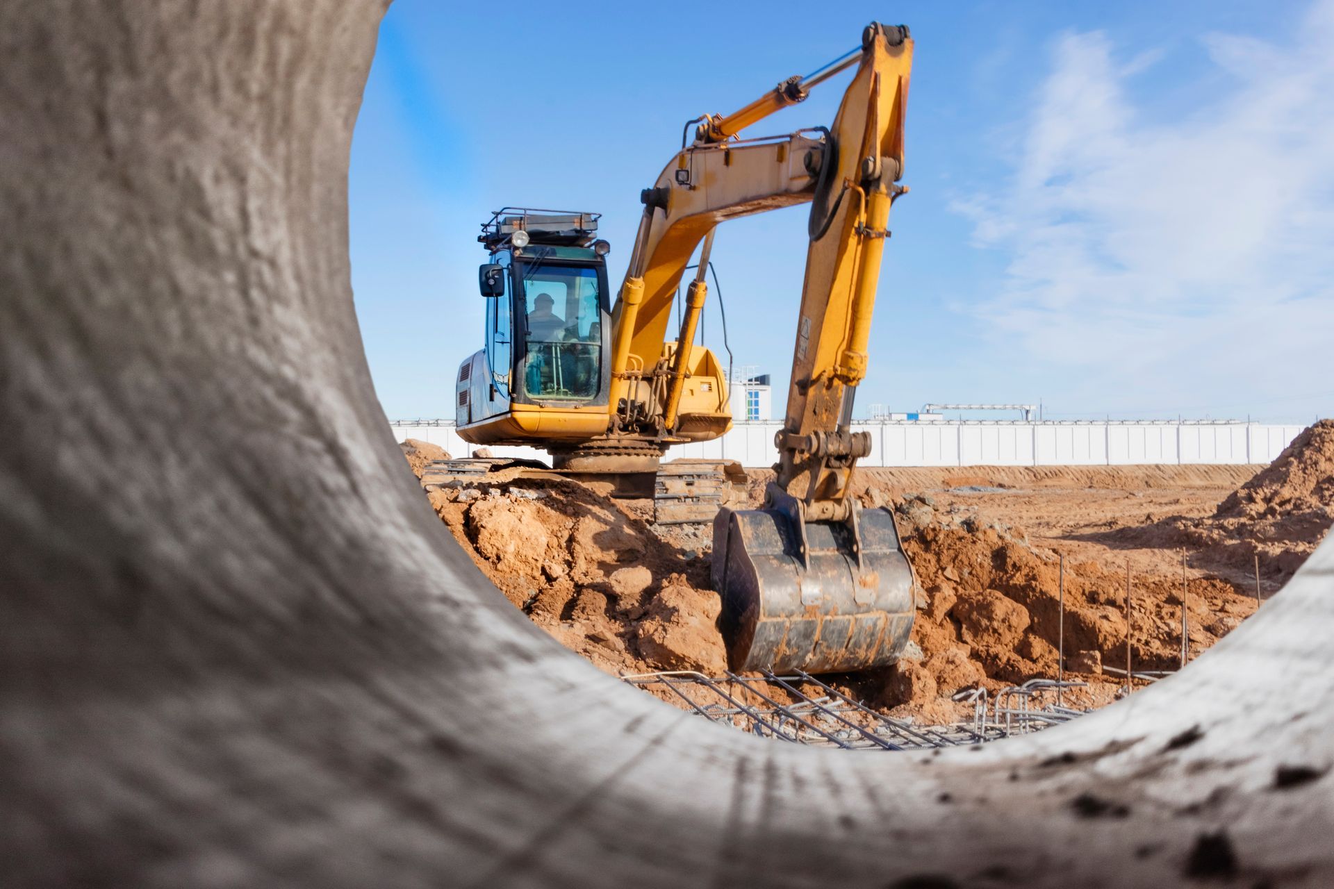Une pelleteuse sur un chantier vue à travers une canalisation.