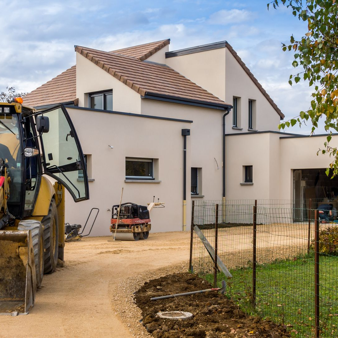 Une tractopelle sur un terrain viabilisé pour une maison neuve.