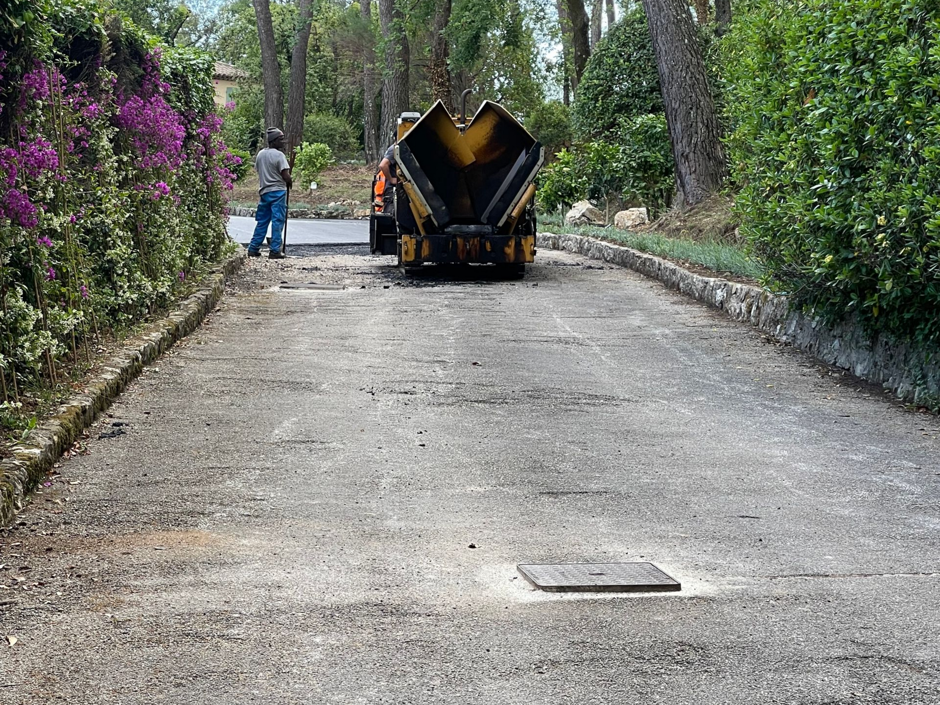 Une machine pose de l'enrobé noir sur une allée résidentielle.