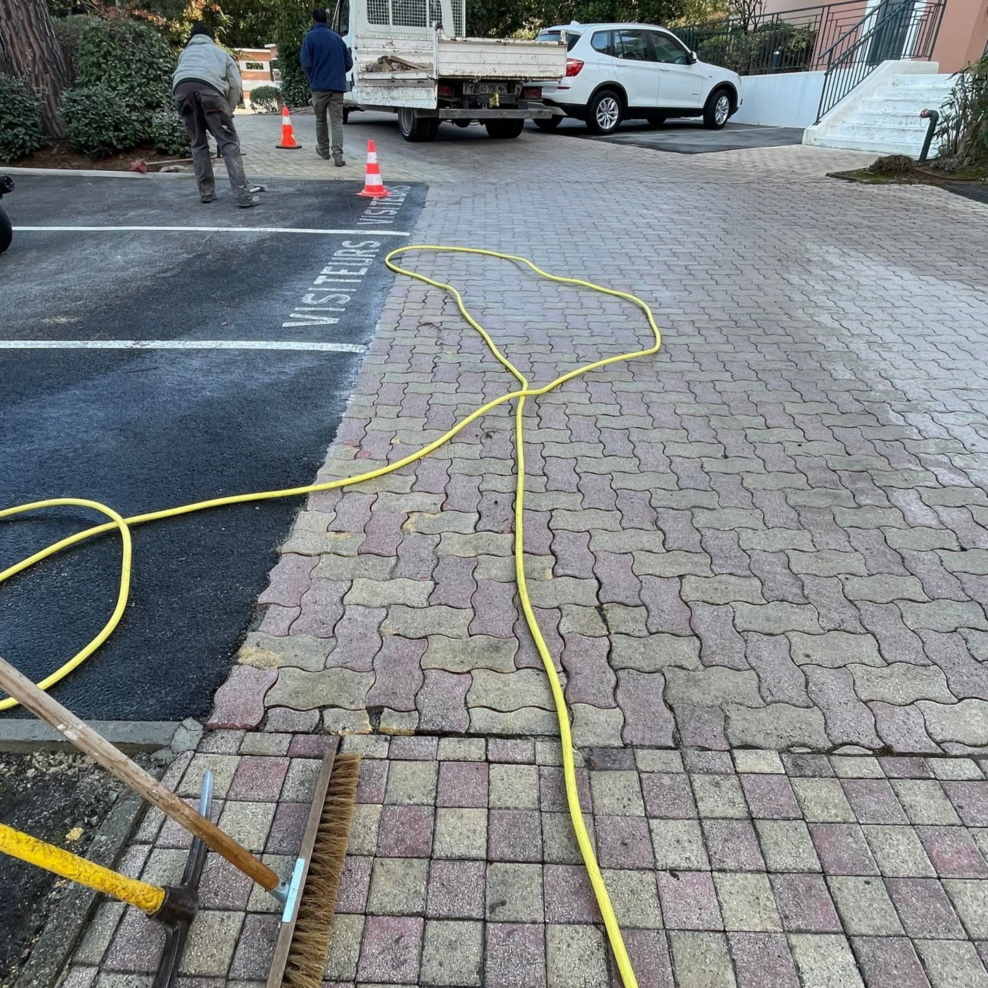 Des ouvriers réparent l'espace pavé d'un lieu public.