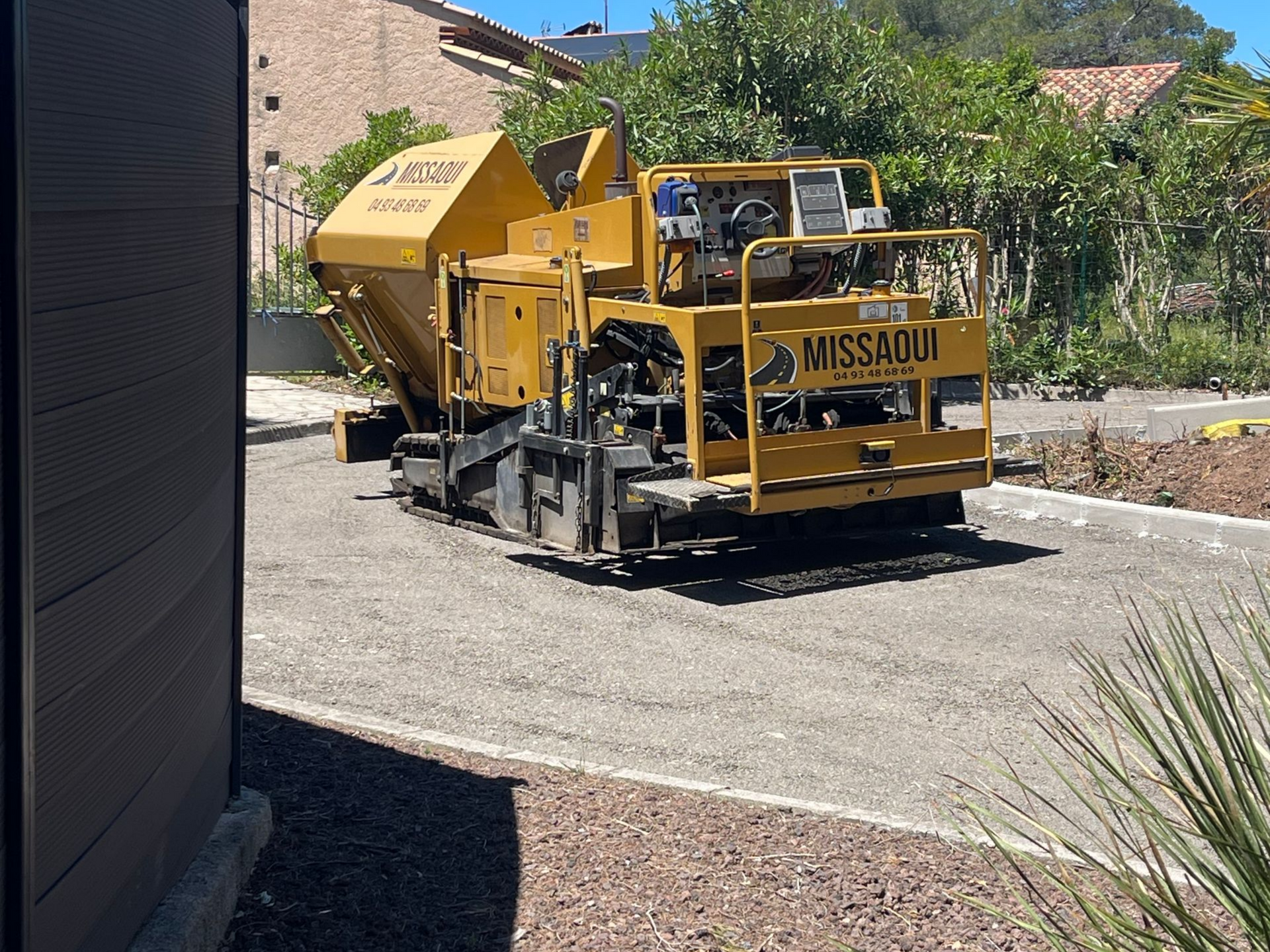 Engin de chantier sur une allée avec des bordures béton.