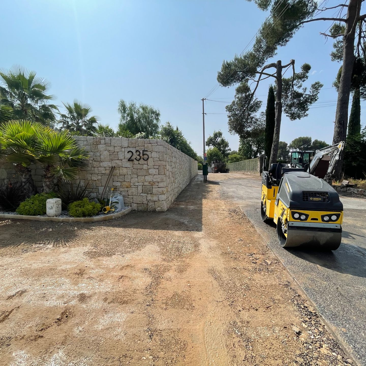 Rouleau compresseur jaune compacte un enrobé fraîchement posé.