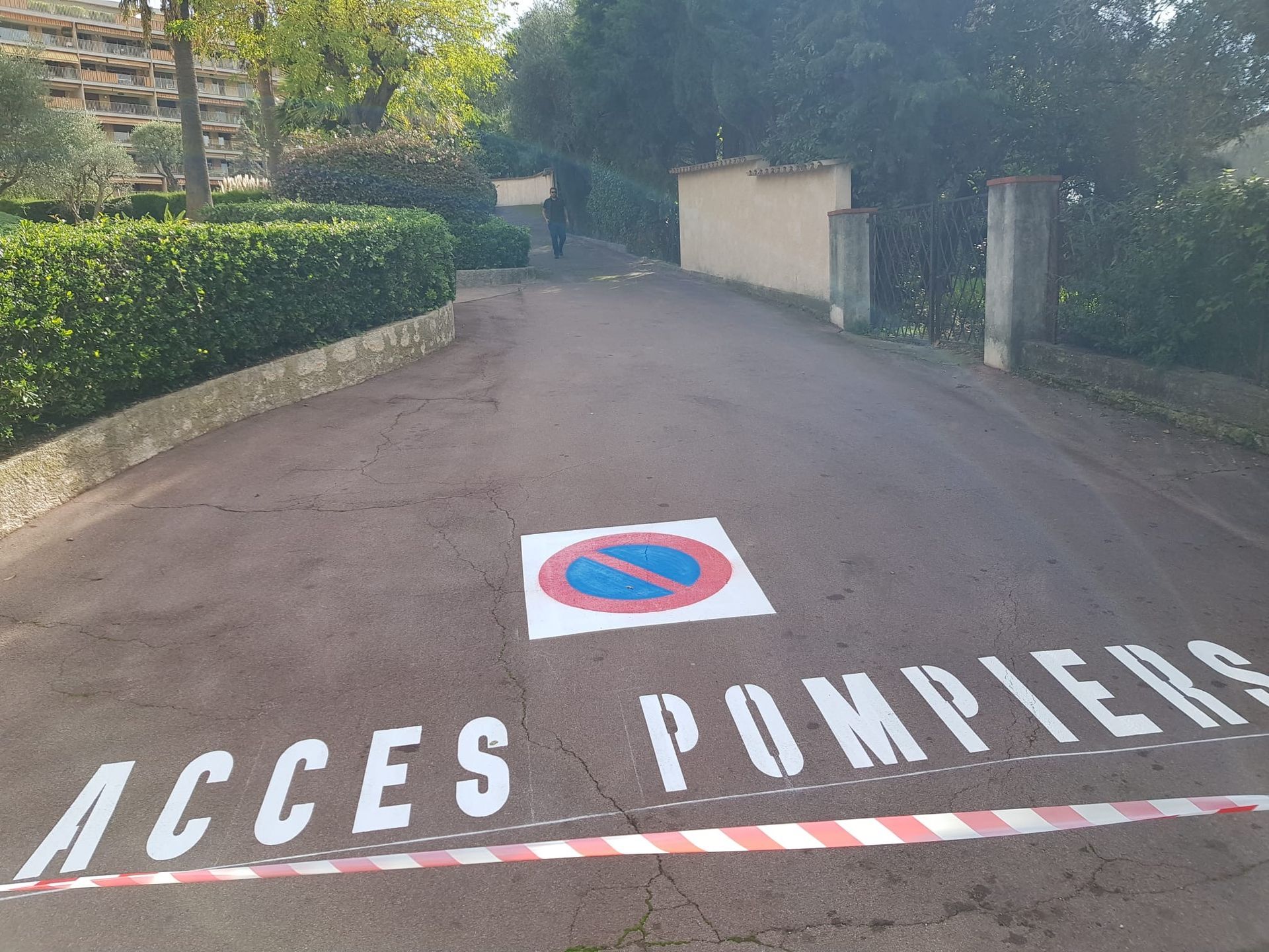 Marquage d'un accès pompier sur une allée en enrobé rouge.