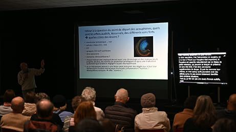 Un homme présente une diapositive lors d'une conférence devant un public.