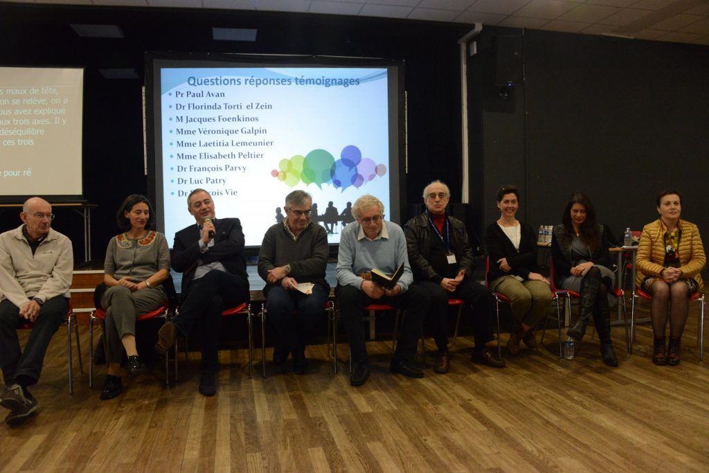 Un groupe de personnes assises à une table devant un écran diffusant une présentation.