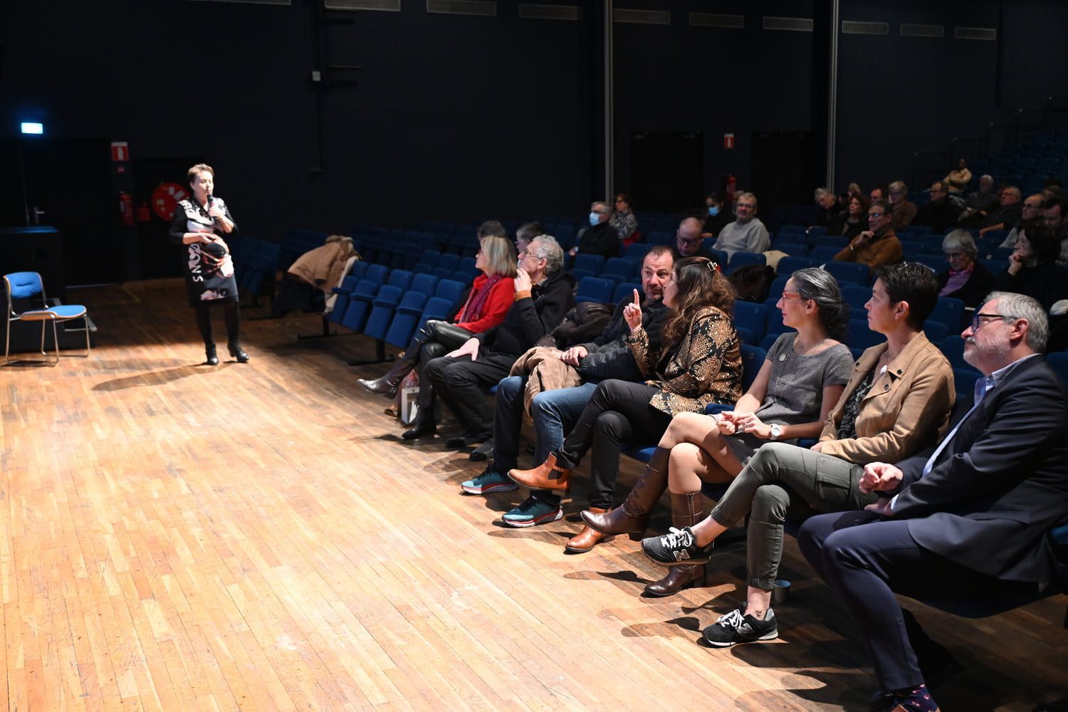 Le public regarde une présentation sur écran dans une salle de cinéma obscure.