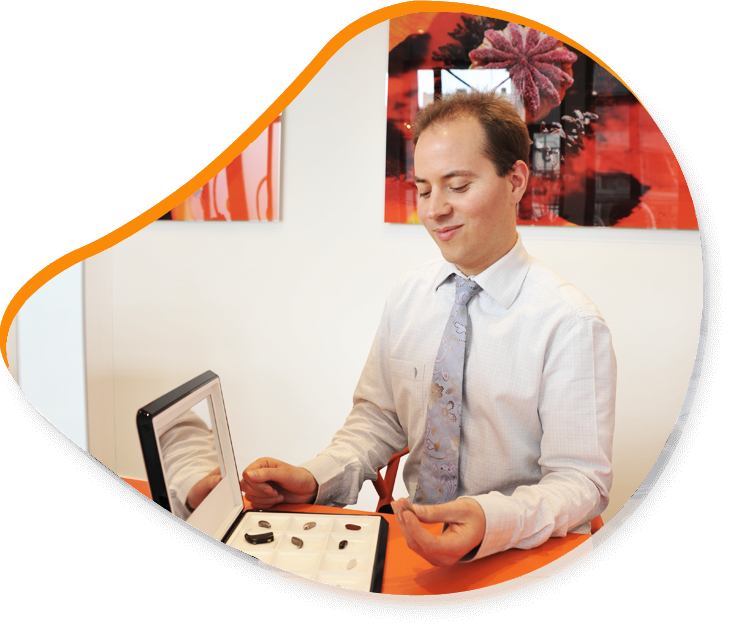 Un homme examine des appareils auditifs à une table dans un bureau.