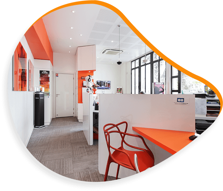 Intérieur de bureau avec des touches d'orange, des murs blancs, de la moquette grise, une chaise rouge et des bureaux.