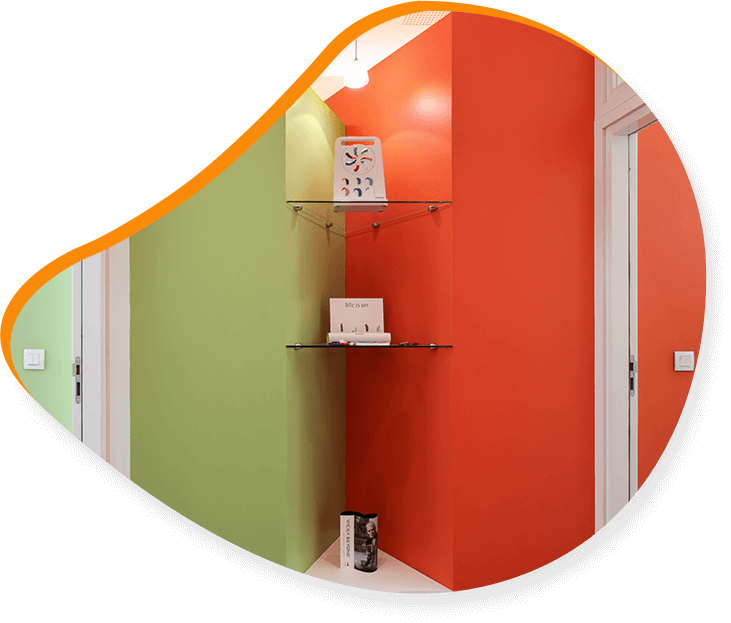 Couloir vert et orange avec des étagères en verre abritant des appareils électroniques, flanqué de deux portes blanches.