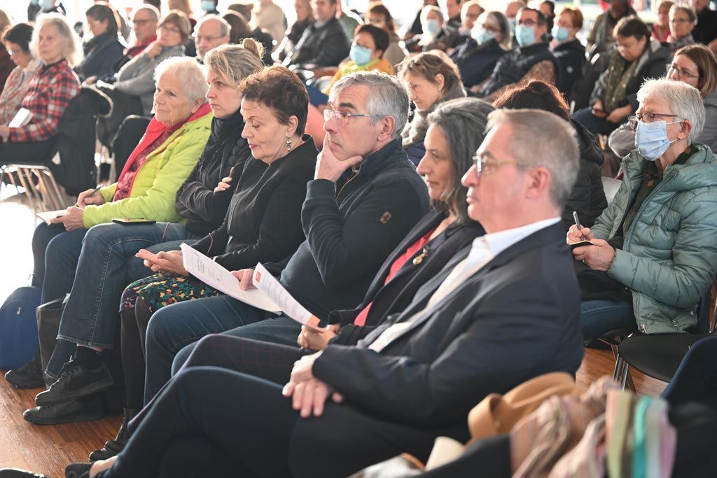 Le public est assis à l'intérieur, assistant à un événement. 