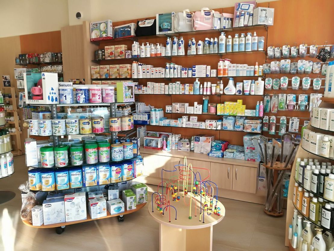 El interior de una farmacia bien iluminada, con estantes repletos de leche de fórmula para bebés, productos para el cuidado de la piel y diversos artículos para la salud.