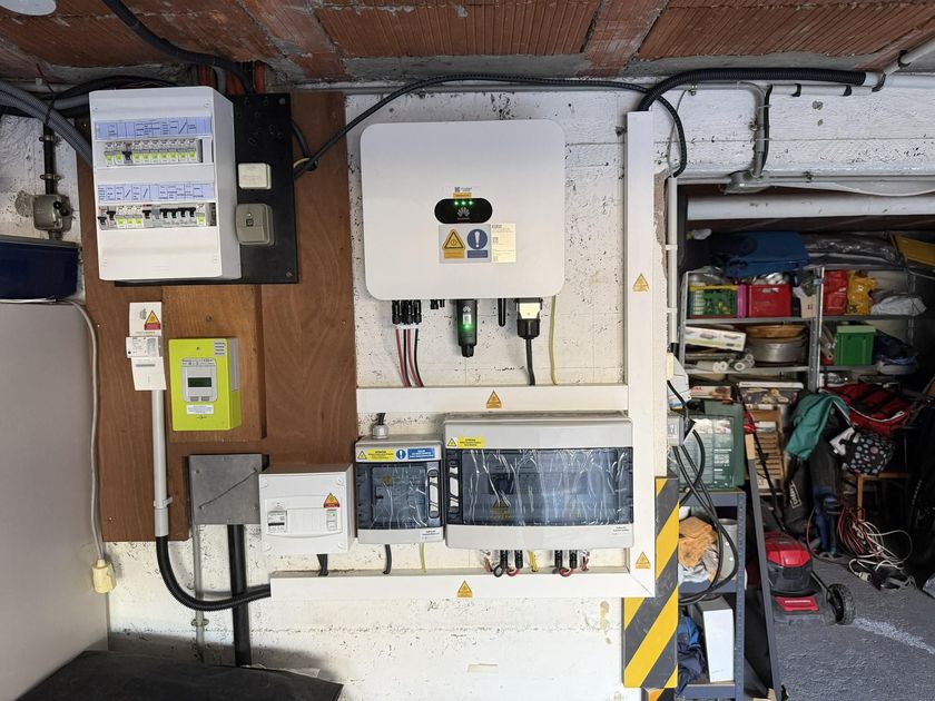 Tableaux électriques et câblage dans une buanderie, avec des étagères et des outils à proximité.