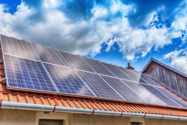Panneaux solaires installés sur un toit sous un ciel bleu nuageux.
