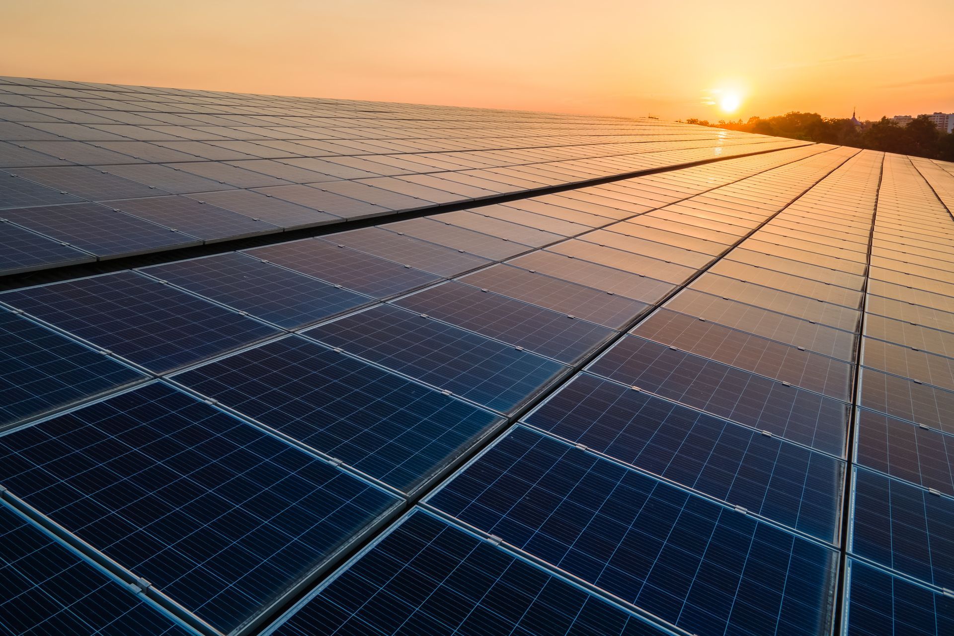 Des panneaux solaires s’étendant à perte de vue au coucher du soleil, sur un toit ou dans une ferme solaire.