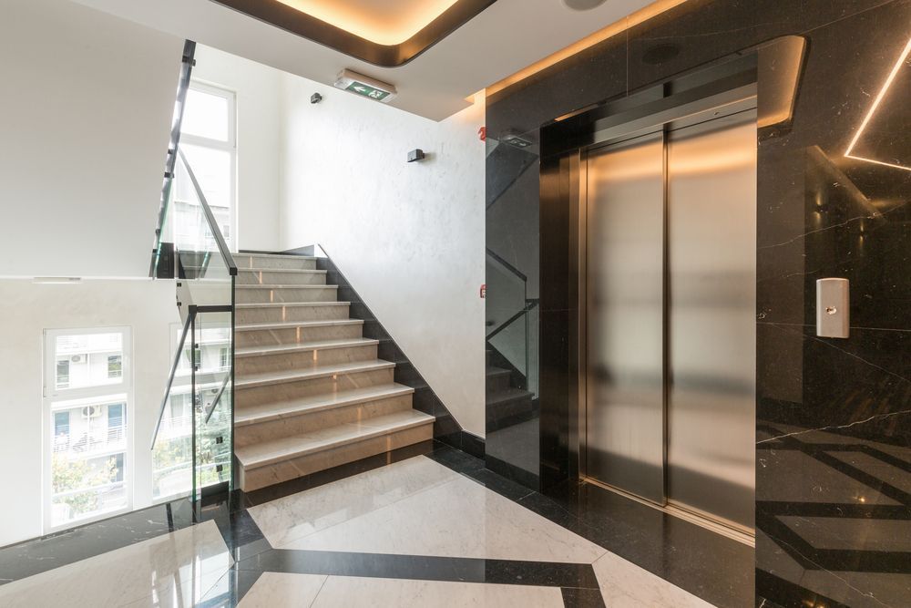 Un pasillo con escaleras y ascensor en un edificio.
