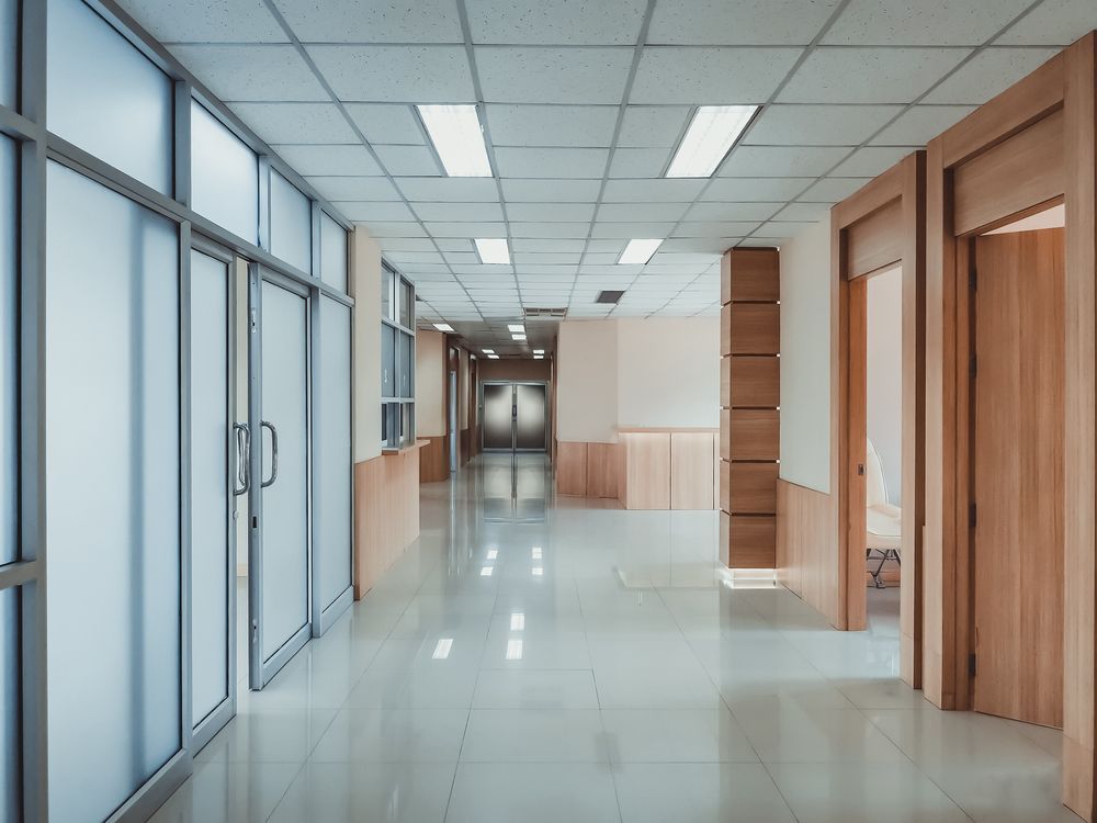 Un pasillo de hospital vacío con muchas ventanas y puertas.