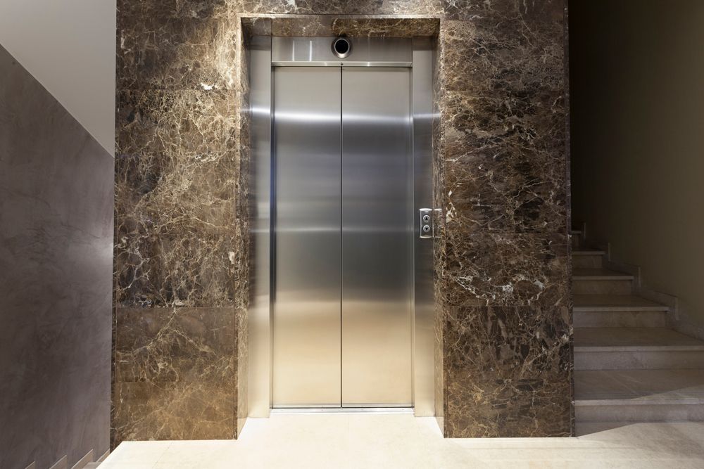 Un ascensor en un edificio con paredes y escaleras de mármol.