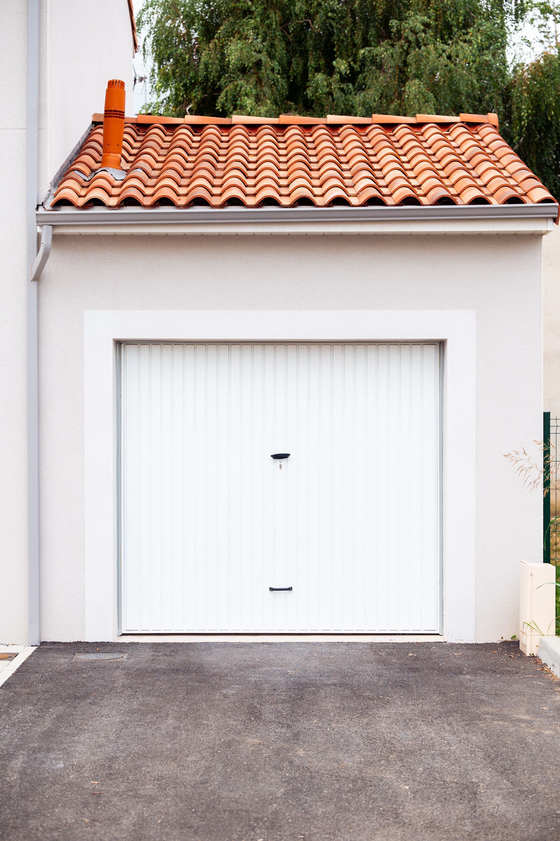 Porte de garage blanche et toiture en tuile orange
