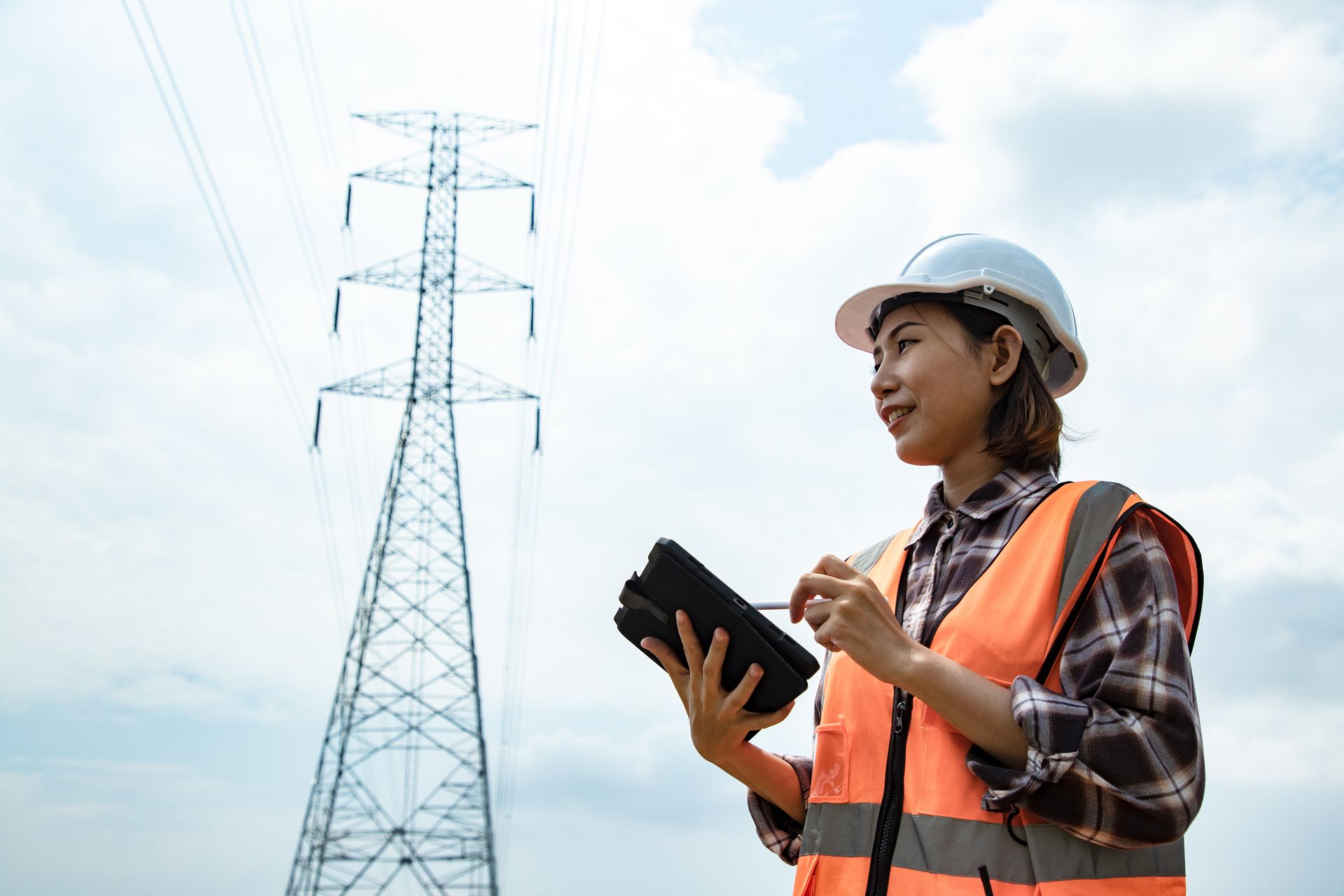 Femme en tenue de chantier observant des lignes électriques