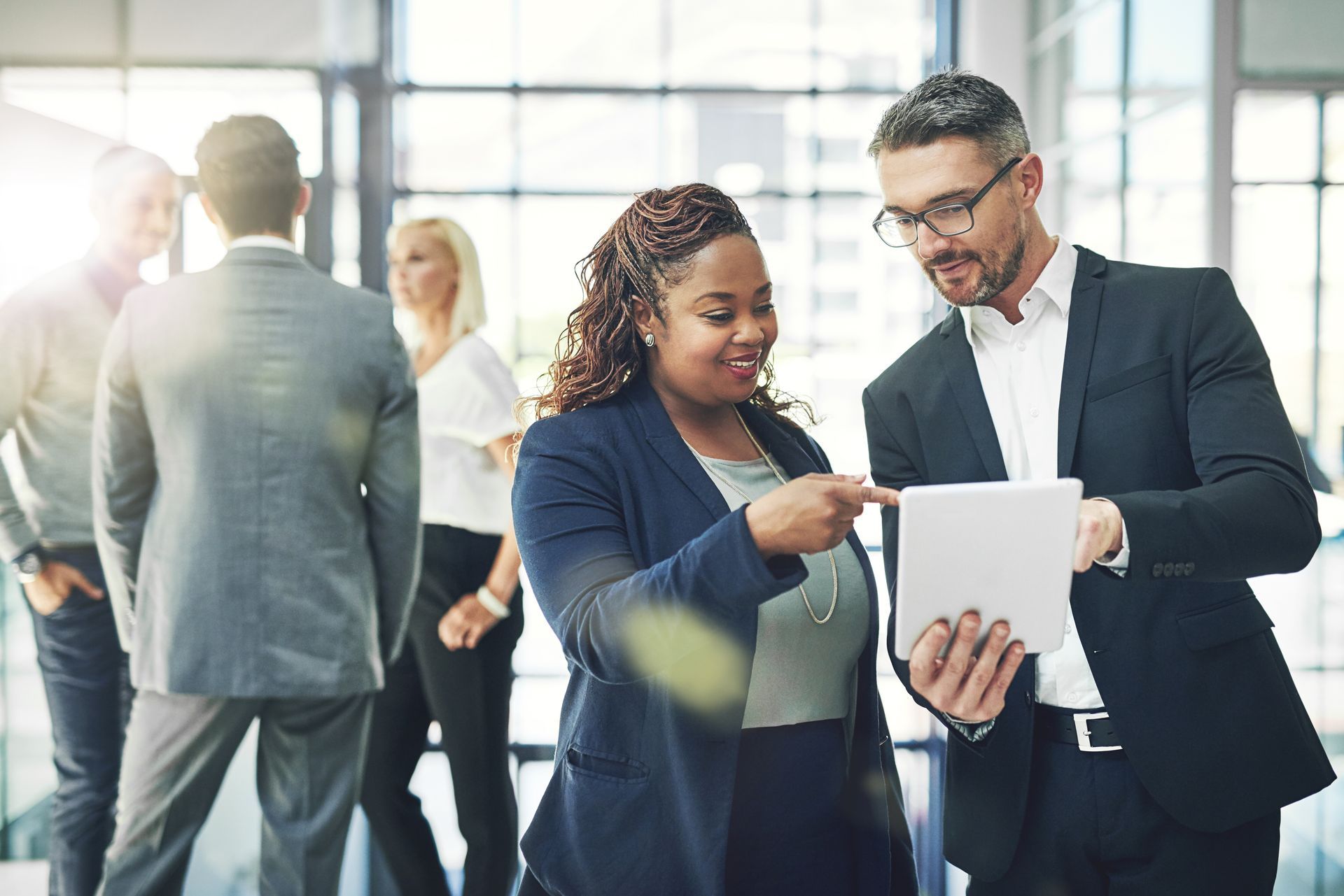 Collaborateurs en discussion dans un cadre professionnel avec une tablette