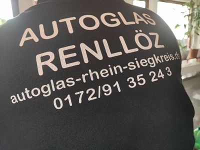 Ein Mann steht in einer Garage neben einem Auto mit geöffneter Motorhaube.