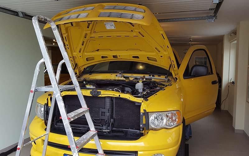 Ein gelber LKW mit offener Motorhaube steht in einer Garage