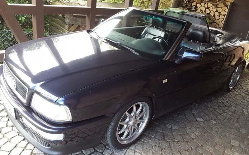 Ein schwarzes Cabrio ist auf einer Kopfsteinpflasterstraße geparkt