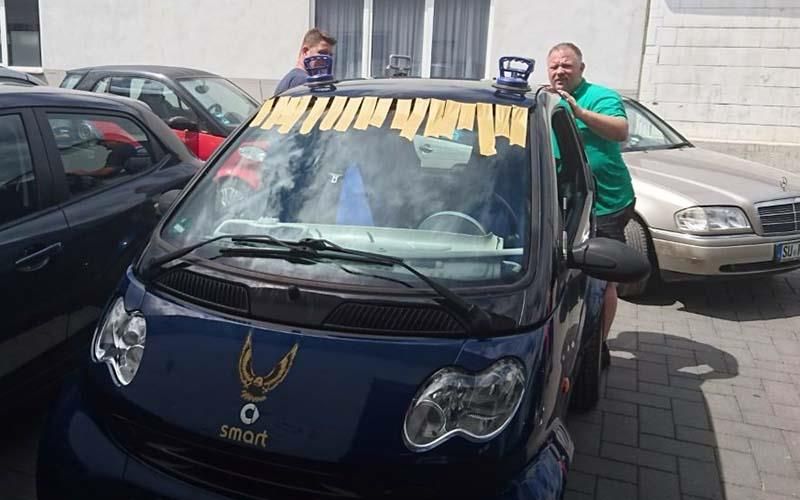 Zwei Männer stehen neben einem Smart